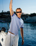 Man on a boat holding onto a rope with water and sky in the background